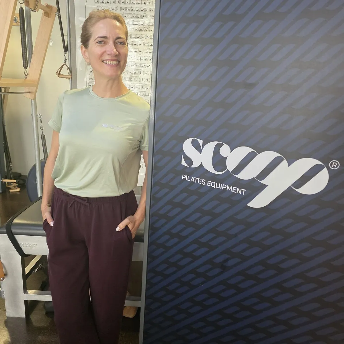 Instrutora de t-shirt verde junto ao painel Scoop do estúdio