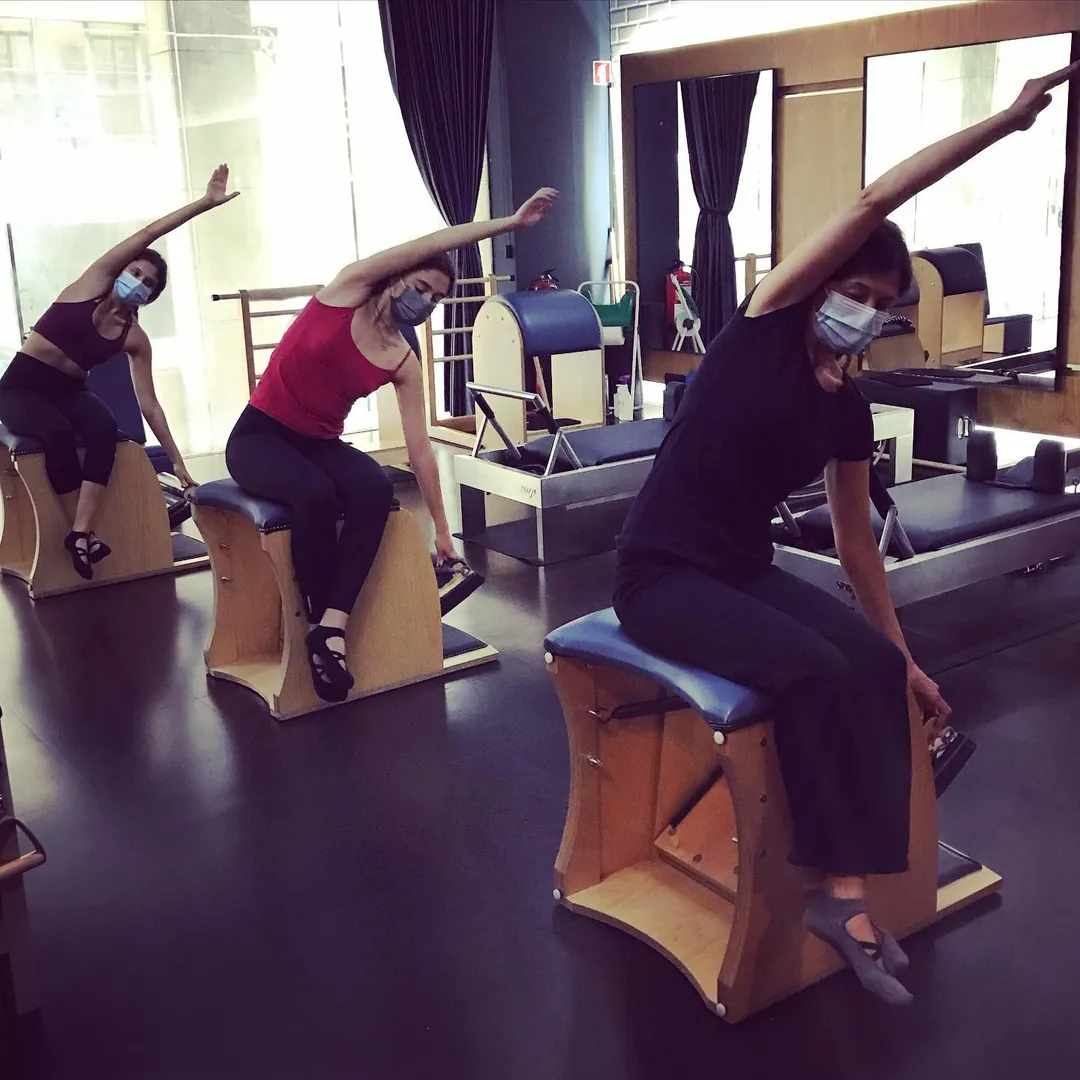 Três alunas sentadas em wunda chairs, com os braços estendidos para o lado